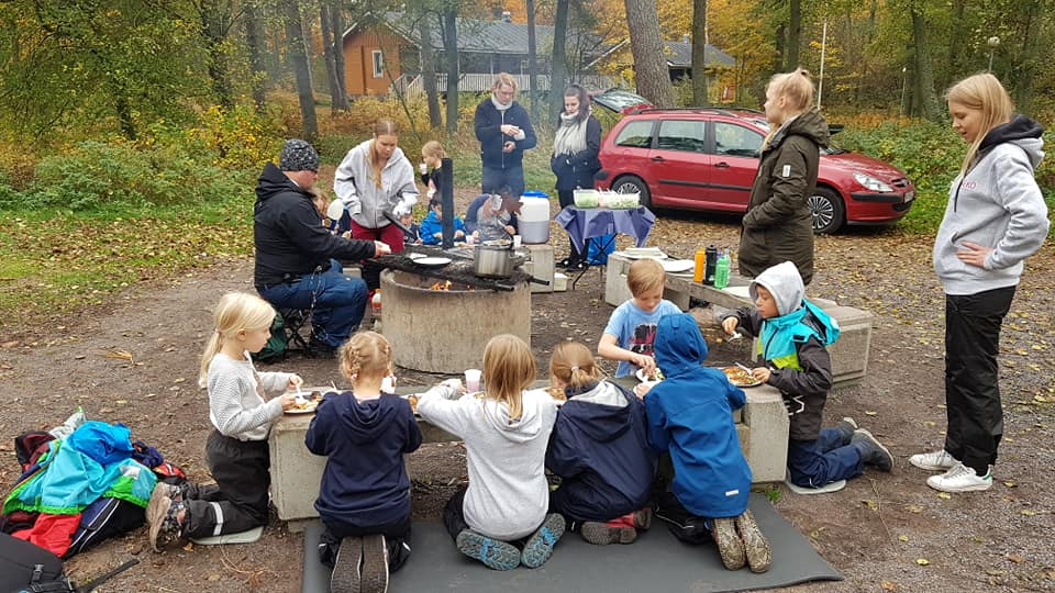 Lapsia ulkona syömässä grilli makkaraa.