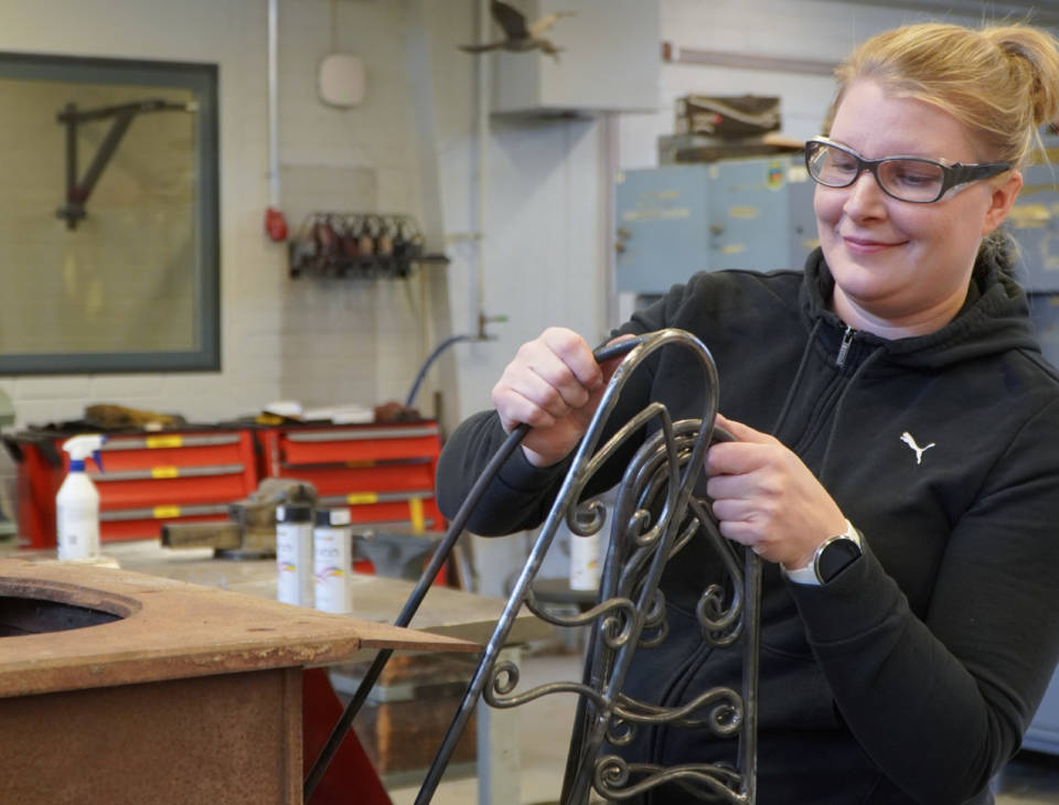 Henkilö asettelemassa metalliosia yhteen.