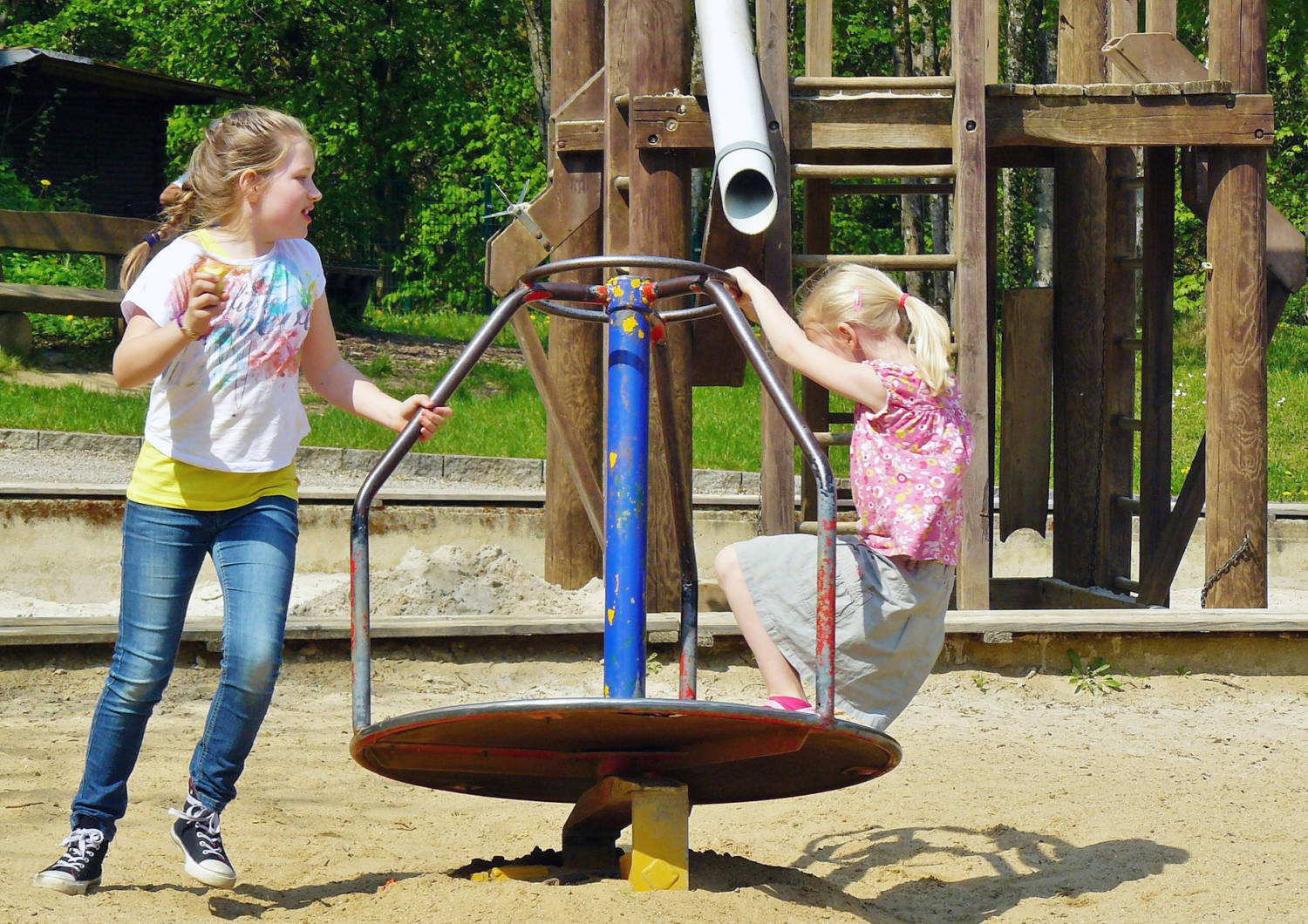 Koululaiset leikkivät puiston karusellissa.
