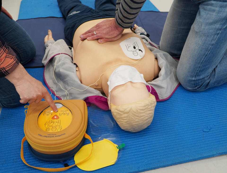 Kaksi henkilöä harjoittelee elvytystä defibrillaattorin avulla.