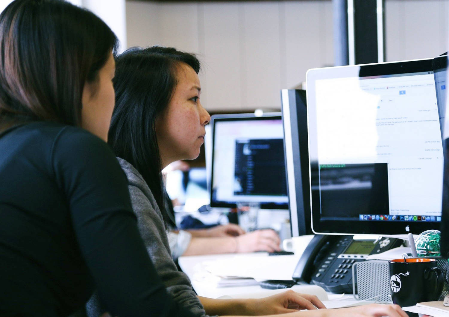 Kaksi naista tietokonenäyttöjen edessä työskentelemässä.
