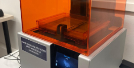 close up view of a 3D printer with orange plastic cover and small digital touch screen