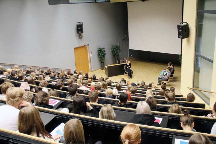 Auditorion yleisö takaa päin, edessä opetusministeri Andersson ja kolme opiskelijaa.