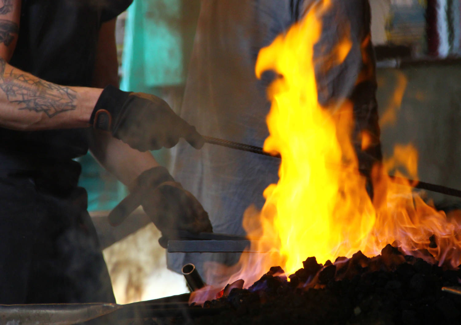 Kuvassa henkilö kuumentaa metallia ahjossa olevassa tulessa.