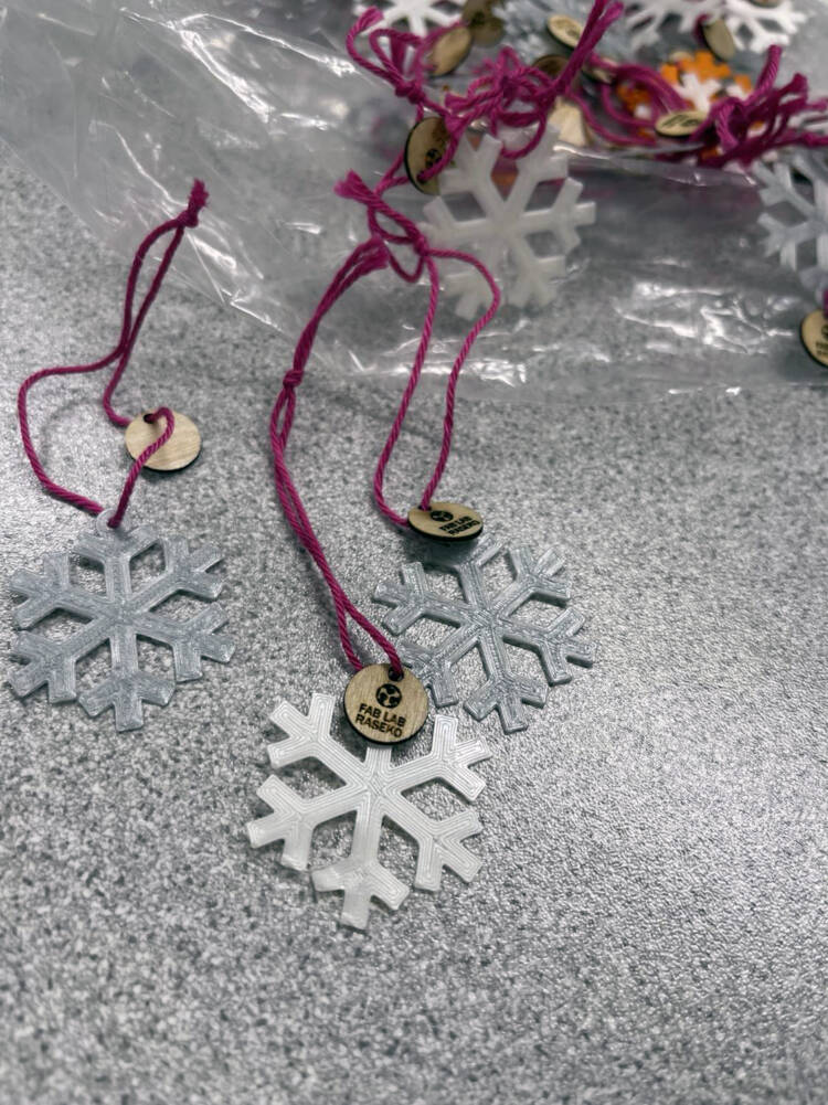 Lumihiutaleen mallisia hopean värisiä koristeita pöydällä.
