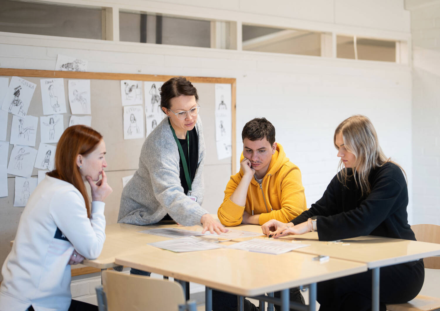 Three people sitting and a fourth standing to side.