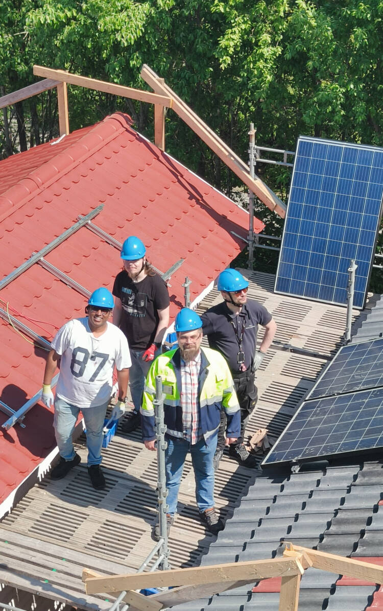 Neljä ihmistä katolla katsoen ylös kohti kameraa.