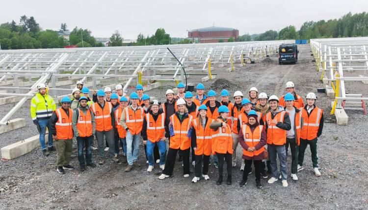 A group of people in a solar power park wearing work clothes.