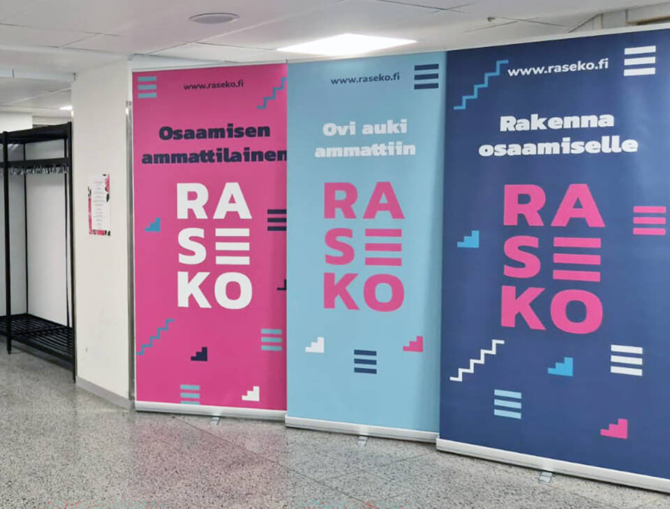 Pinkki, turkoosi ja sininen Rasekon rollup-mainos rivissä.
