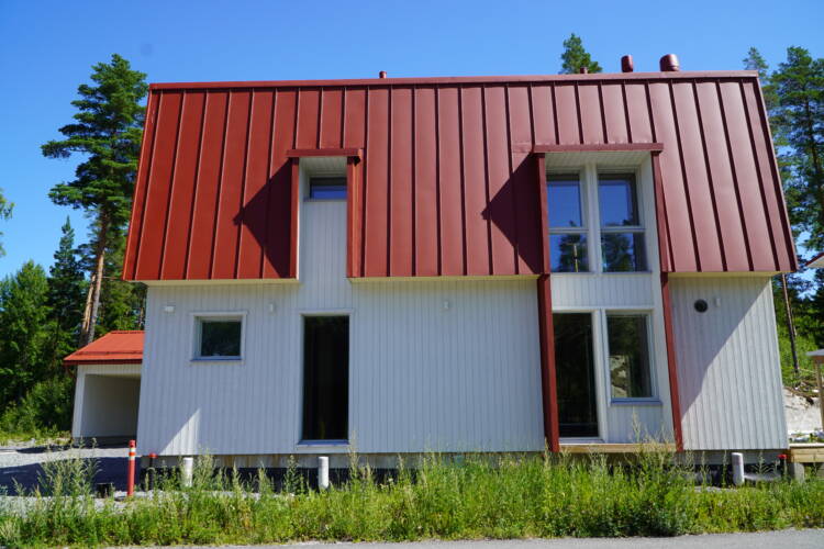 Valkoinen puuverhoiltu omakotitalo, jossa punainen peltikatto.
